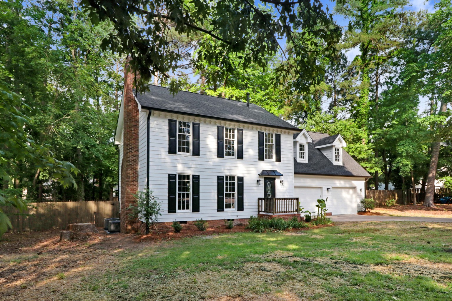 Fully renovated two-storey home in the Triangle with white siding, black shutters and a new front porch