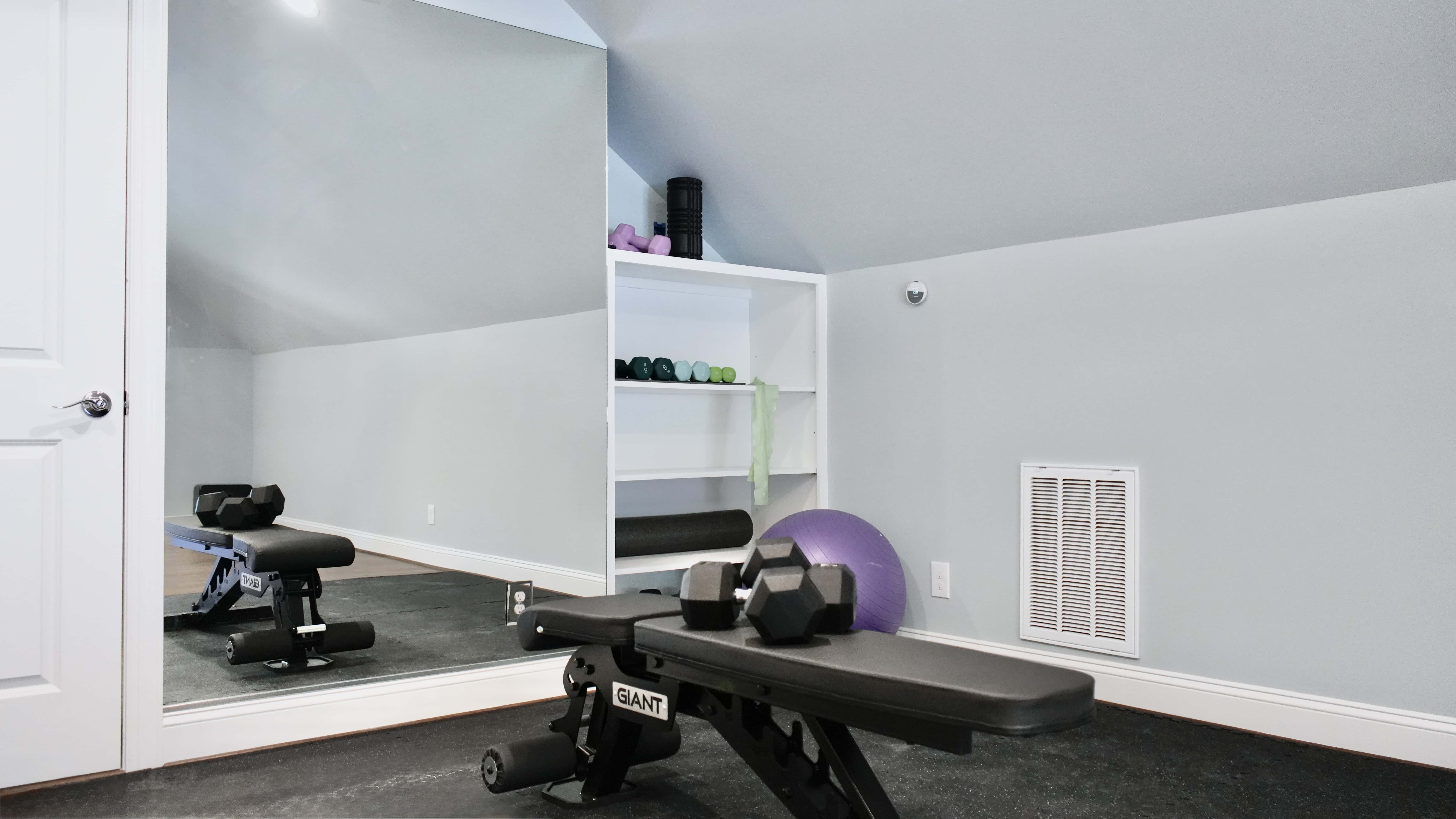 Finished attic home gym with a full-height mirror, built-in shelving and rubber flooring
