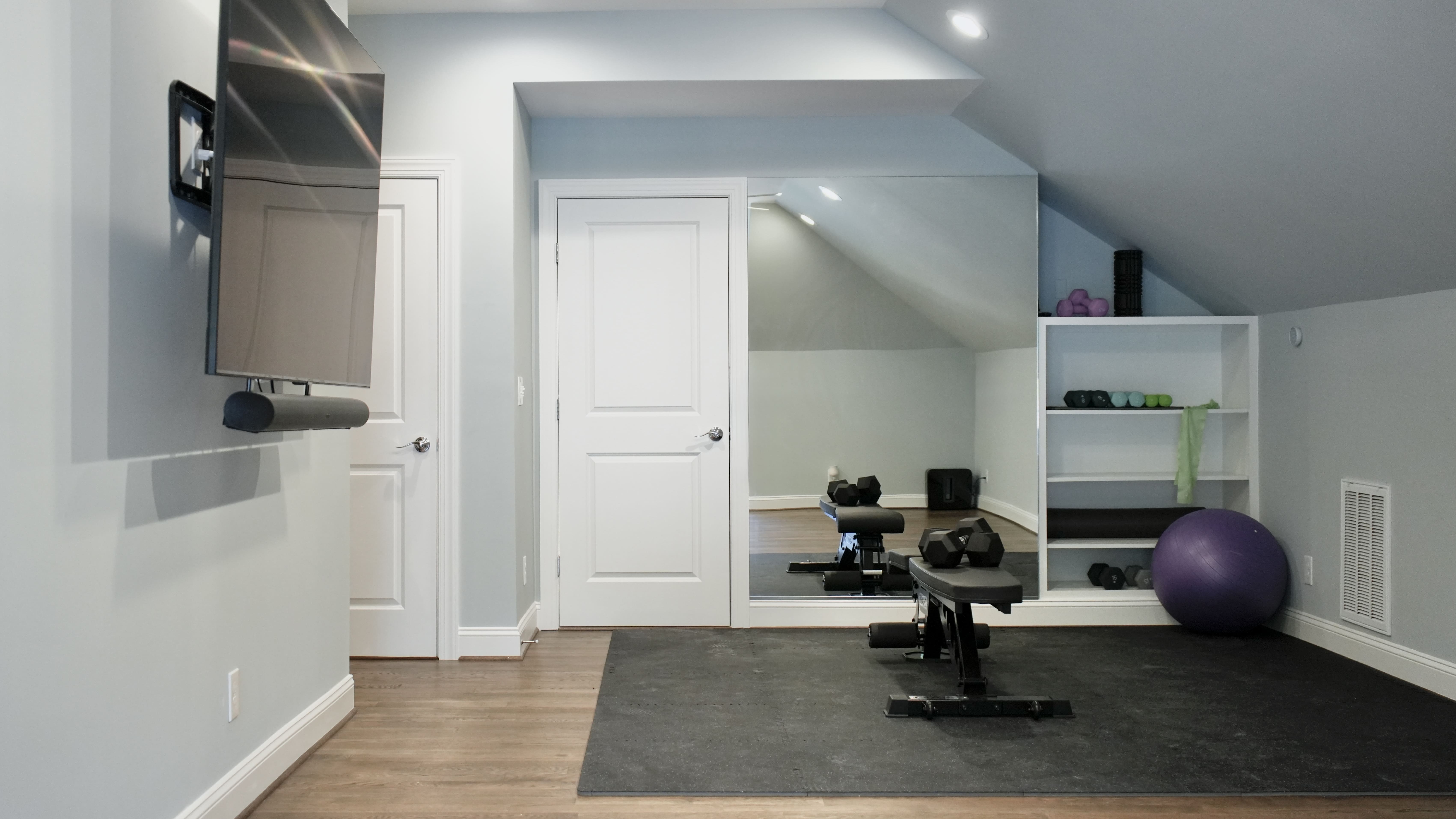 Finished attic fitted out as a home gym, with a full-height mirror and built-in shelving