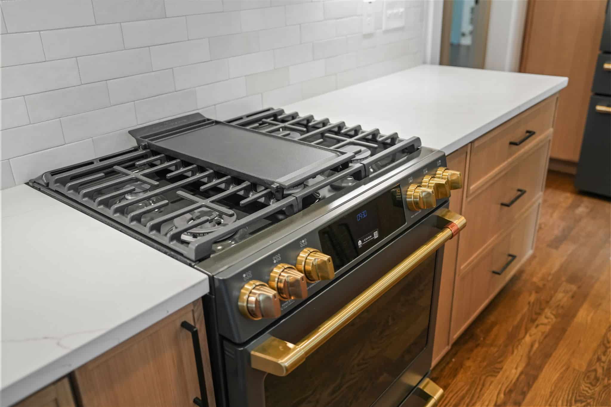 Professional gas range with brass knobs set into a quartz countertop