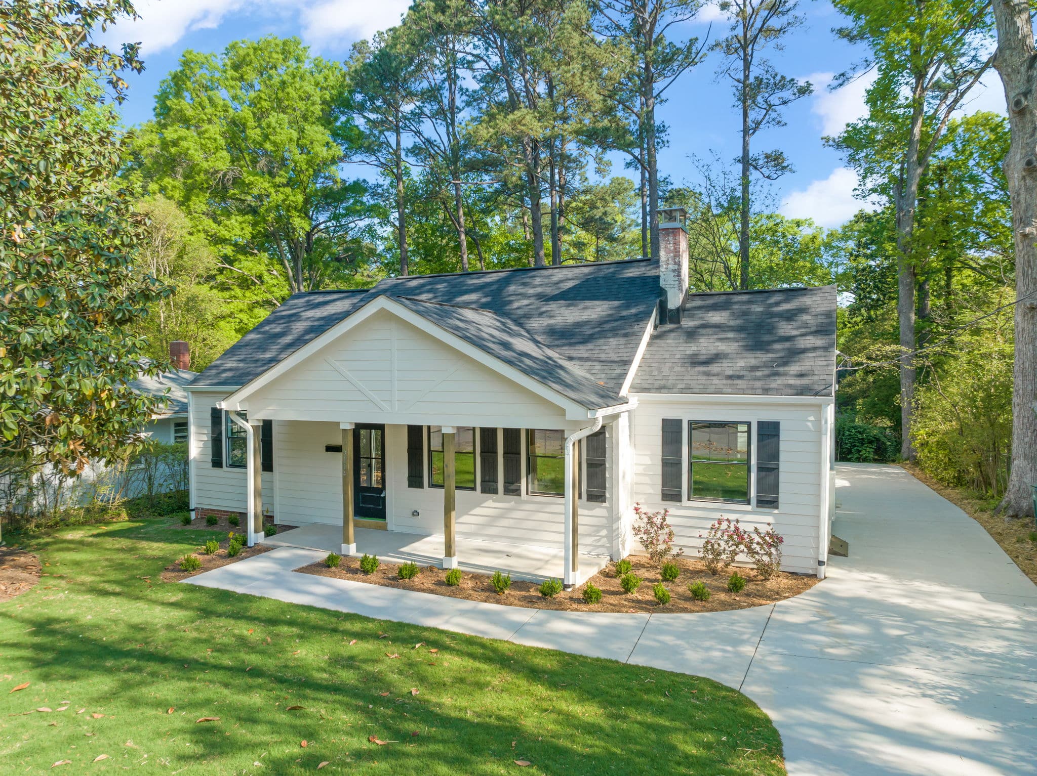 Renovated white cottage in Raleigh with a new covered front porch and planted beds