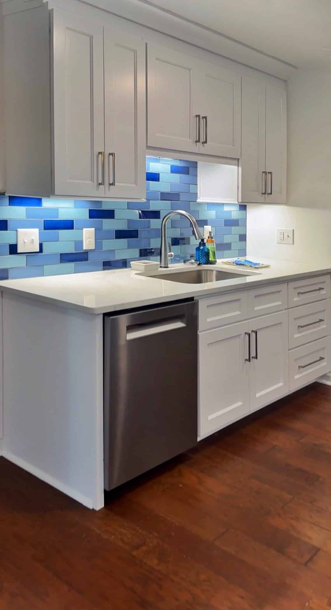 Renovated kitchen with white shaker cabinetry, quartz worktops and a blue glass tile backsplash