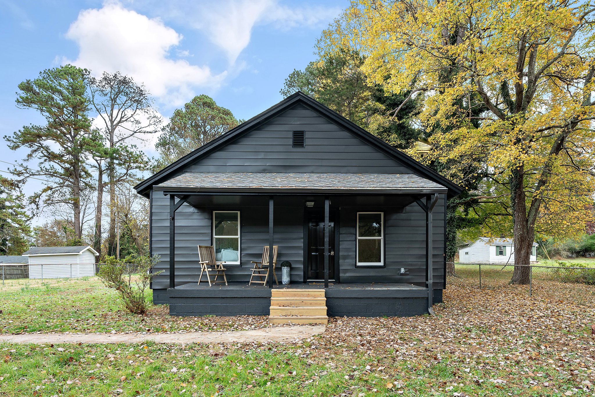 Renovated single-storey home with dark siding, white trim and a covered front porch